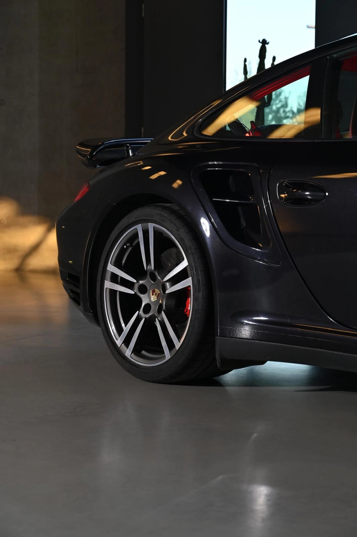 Tylne koło i bok czarnego Porsche w ciepłym świetle